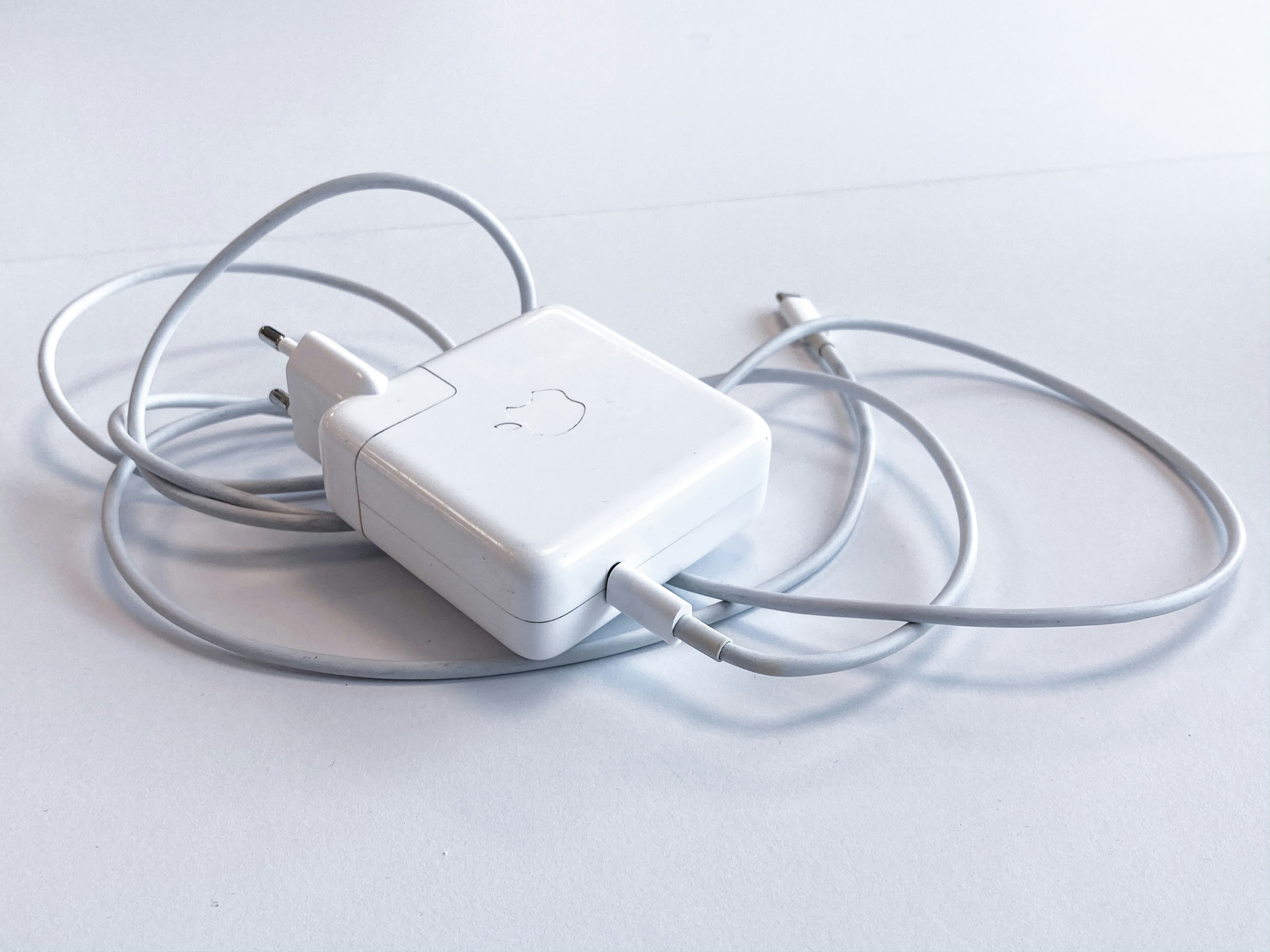 MacBook charger cable on clean white surface, minimal tech product photo