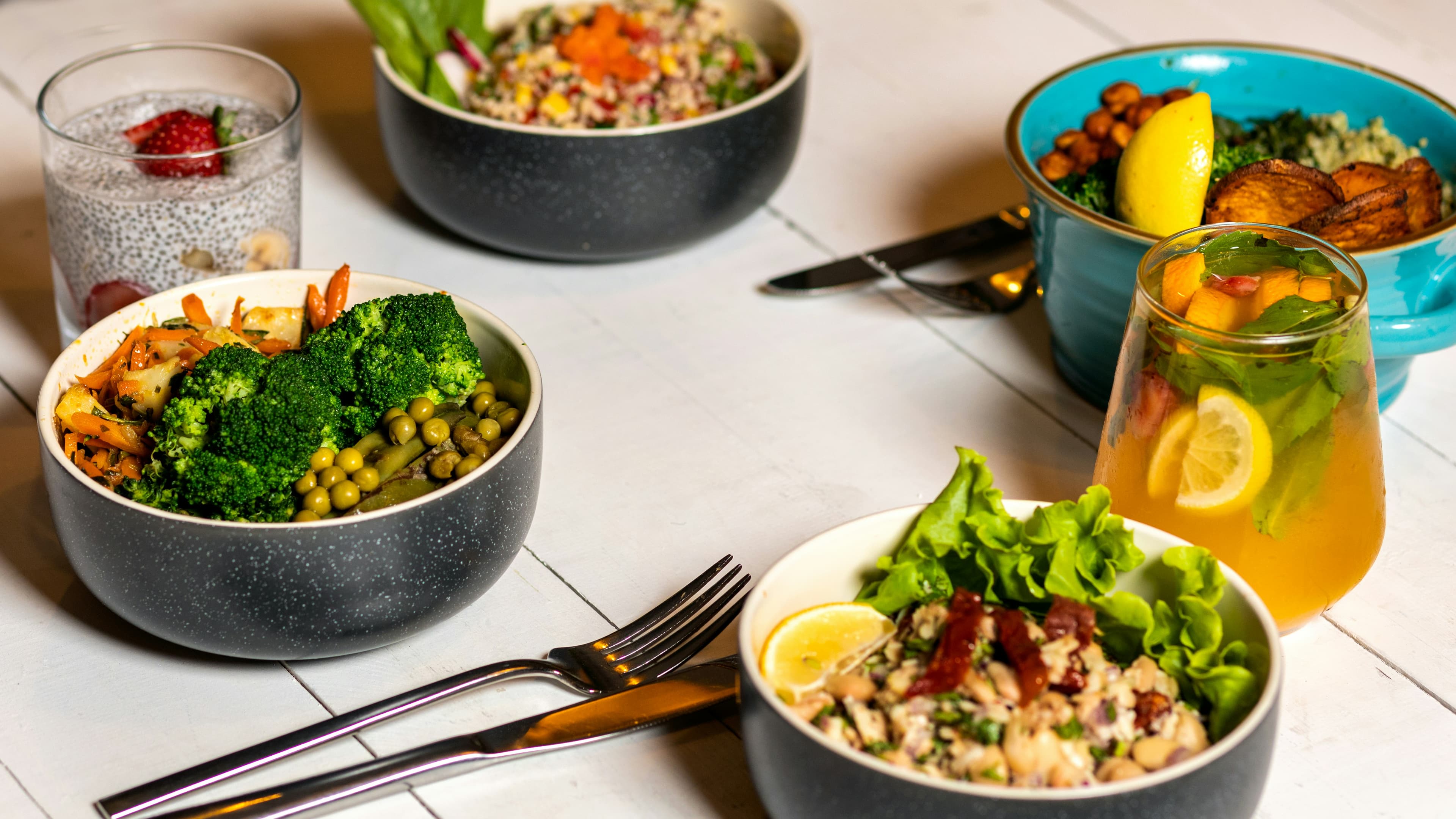Colorful healthy grain bowls with fresh vegetables on clean white table, bright studio lighting