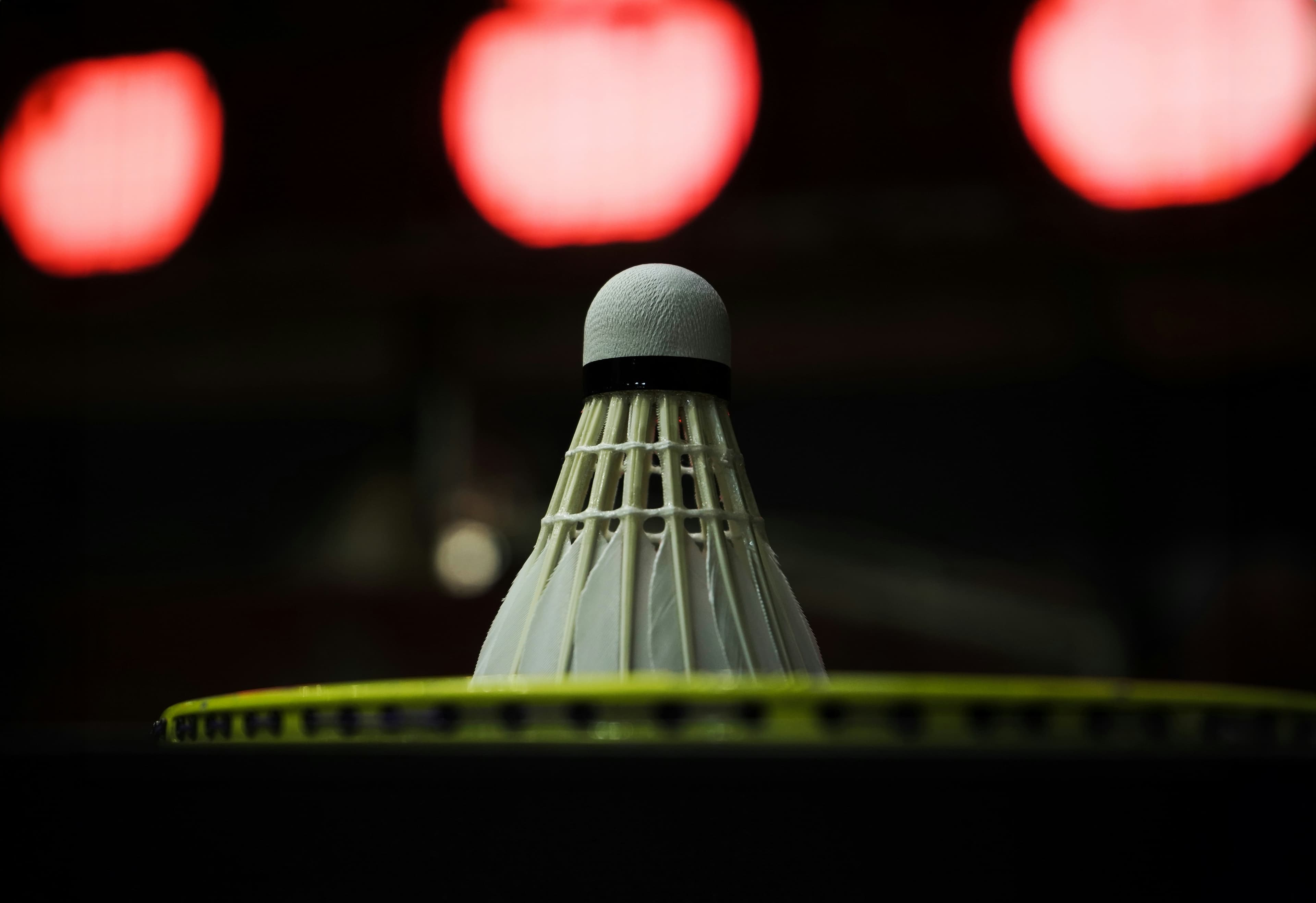 Badminton racket on gym floor with shuttlecock, bright indoor lighting